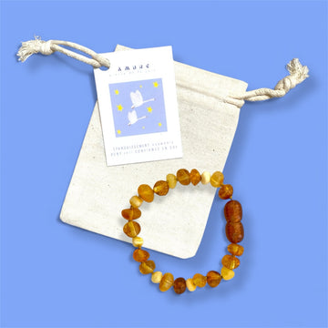Bracelet Bébé KEUR en ambre présenté avec sa pochette sur fond bleu