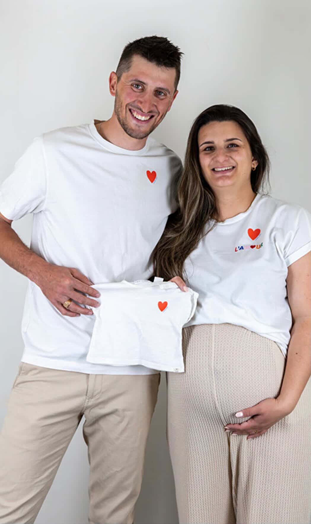 Photo d’un couple souriant tenant un vêtement de bébé.